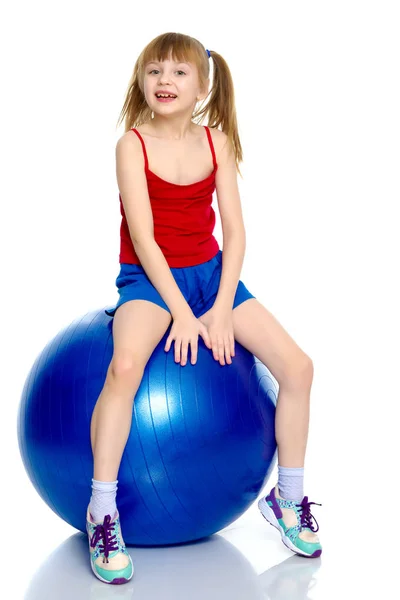 Een klein meisje is springen op de grote gym bal. — Stockfoto