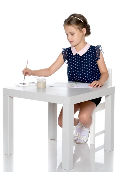 Une petite fille peint avec de la peinture et un pinceau . — Photo