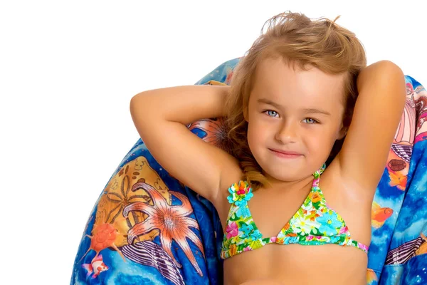 Niña en traje de baño está sentada en una almohada . — Foto de Stock