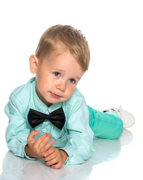 Een kleine jongen is liggend op de vloer in de studio. — Stockfoto