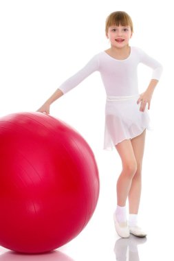 Küçük kız spor yapmak için büyük bir top üzerinde egzersiz yapıyor..