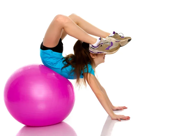 Holčička dělá cvičení na velký míč pro fitness. — Stock fotografie