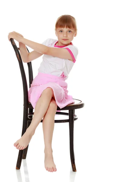Menina está sentada em uma cadeira — Fotografia de Stock