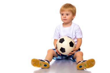 Küçük çocuk bir futbol topuyla oynuyor.