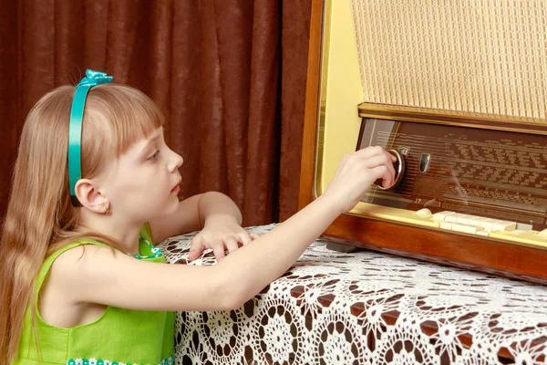 La chica gira la perilla de volumen en la vieja radio. Estilo retro . — Foto de Stock