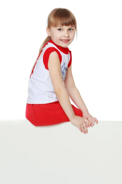 A little girl is looking from behind an empty banner. — Stock Photo, Image