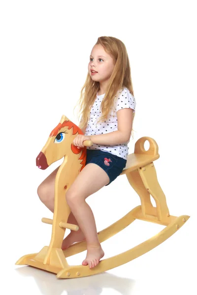 Menina balançando em um cavalo de madeira . — Fotografia de Stock