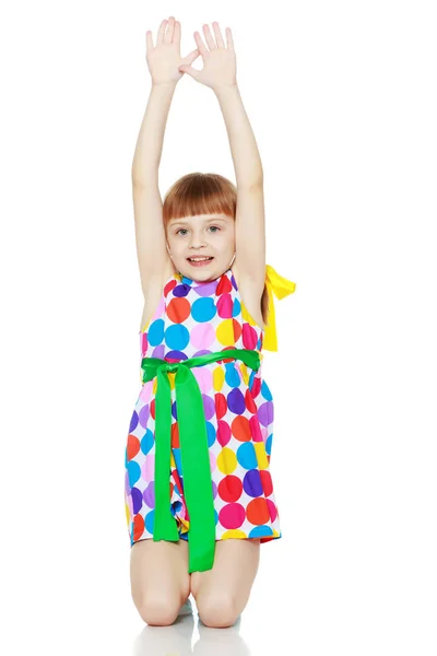 Een klein meisje in een jurk met een patroon van multi-gekleurde circl — Stockfoto