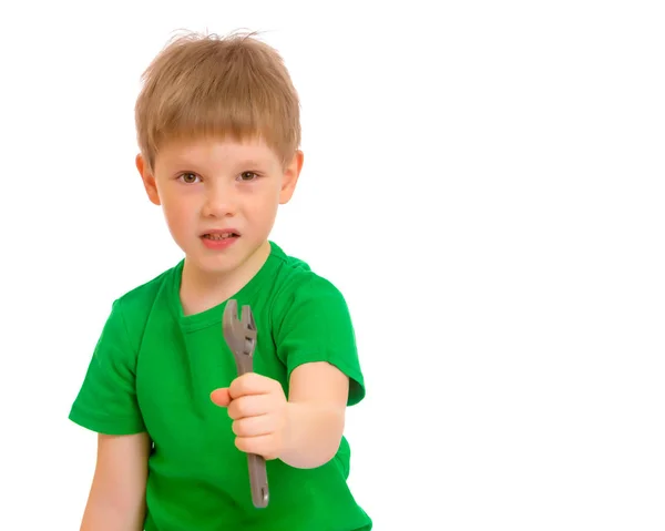 A small boy holds a wrench in his hand. — Stock Photo, Image