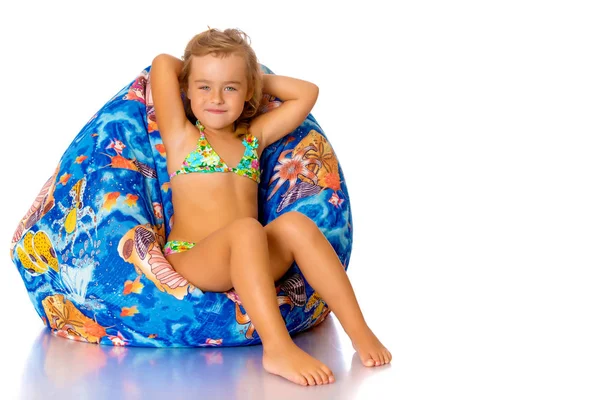 Little girl in a swimsuit is sitting on a pillow. — Stock Photo, Image