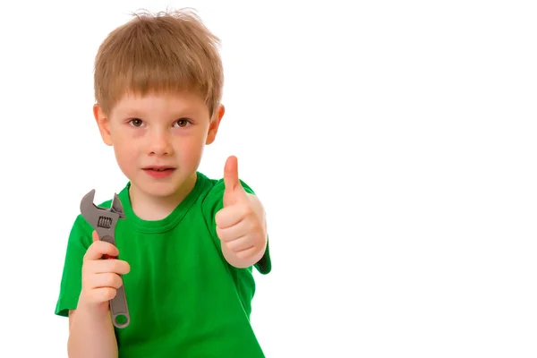 Un niño pequeño sostiene una llave inglesa en su mano . — Foto de Stock