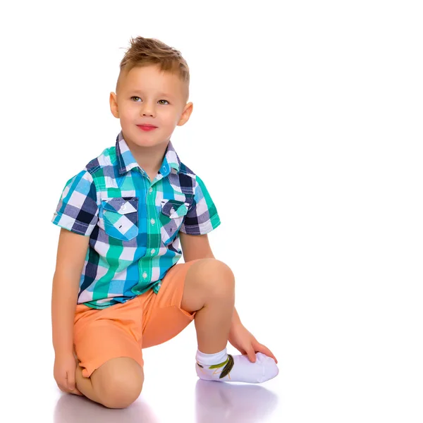 Ein kleiner Junge liegt im Studio auf dem Boden. Stockbild