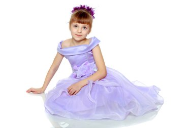 Kız onun önünde katlanmış elleriyle yere oturur.