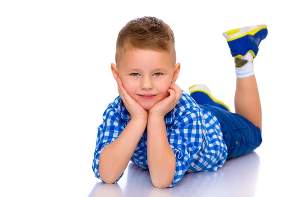 Gelukkig jongetje is liggend op de vloer in de studio. — Stockfoto