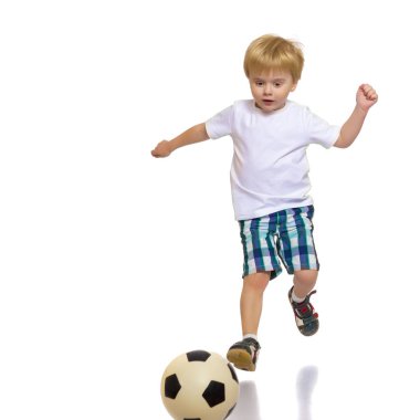 Küçük çocuk bir futbol topuyla oynuyor.