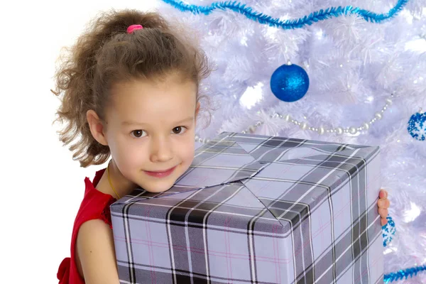 Menina com um presente na árvore de Natal . — Fotografia de Stock