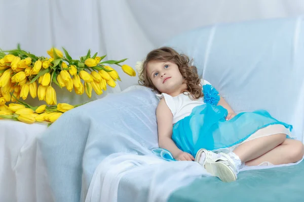 Het kleine meisje op de Bank met een boeket van bloemen. — Stockfoto