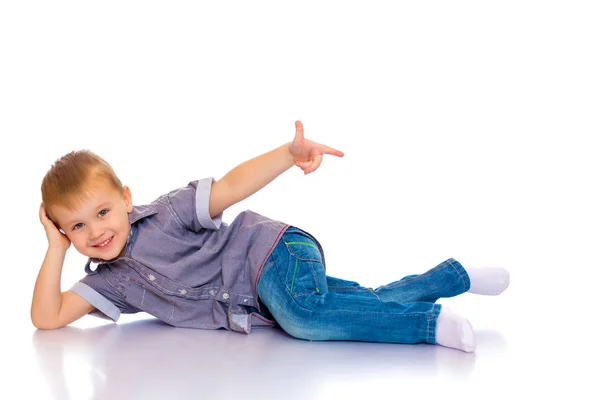 Gelukkig jongetje is liggend op de vloer in de studio. — Stockfoto