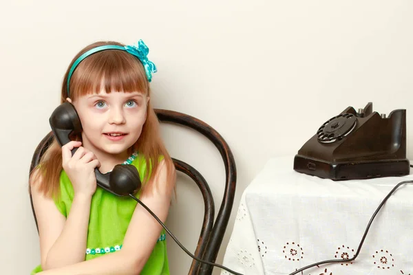 Dívka mluví na černém, starý telefon s rotující disk. — Stock fotografie
