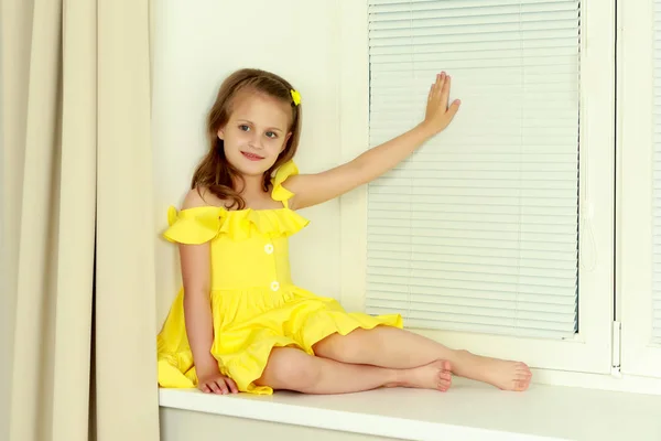 Una bambina è seduta vicino alla finestra con jalousie — Foto Stock