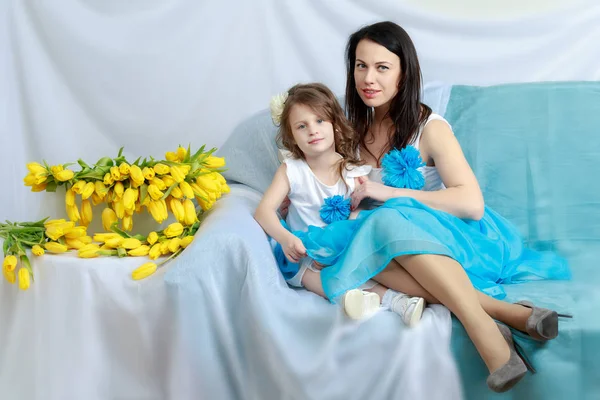Anne ve kızı bir buket çiçek ile kanepede.