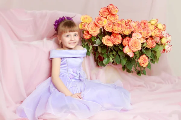 Menina senta-se ao lado de um buquê de flores . — Fotografia de Stock