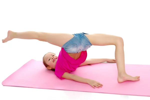 Маленькая гимнастка выполняет акробатический элемент на полу. — стоковое фото