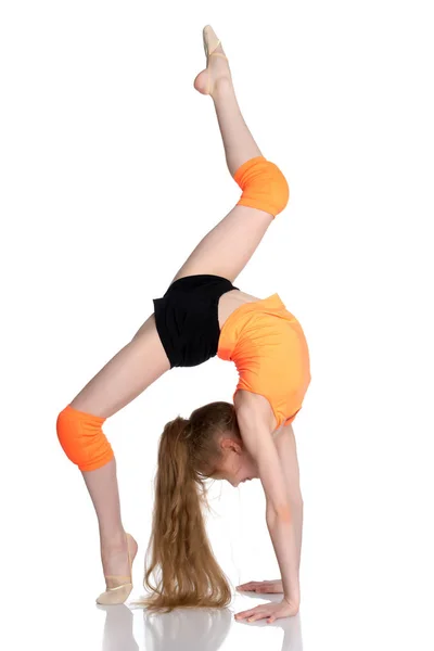 Gimnastyk wykonuje most z podniesionej nogi. — Zdjęcie stockowe