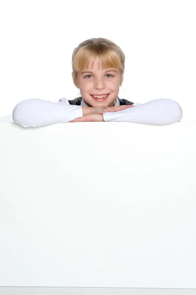 A little girl is looking from behind an empty banner. — Stock Photo, Image