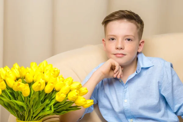 Ein Junge im Schulalter mit einer Blume einer Tulpe. — Stockfoto
