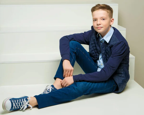 Ein Junge im Schulalter sitzt auf einer weißen Treppe. — Stockfoto