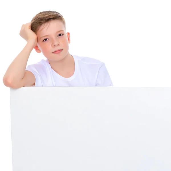 Un niño en edad escolar cerca de una pancarta publicitaria blanca . —  Fotos de Stock