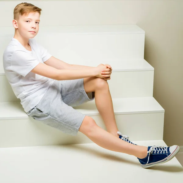 Un écolier est assis sur un escalier blanc. . — Photo