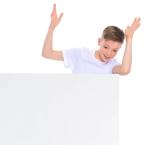 Um menino em idade escolar perto de um banner publicitário branco . — Fotografia de Stock