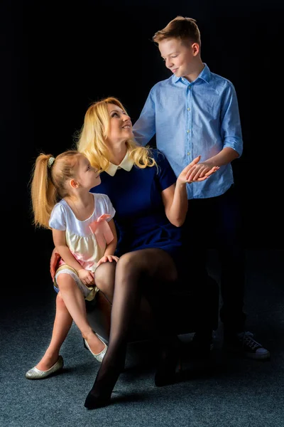 Felice giovane madre con il figlio e la figlia su un backgrou nero — Foto Stock