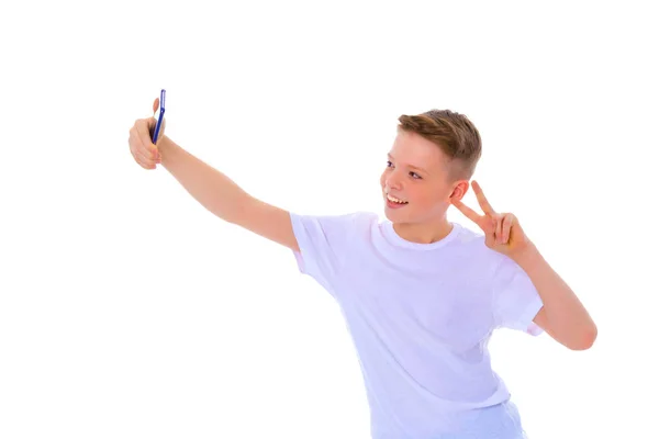 Um menino alegre está fazendo uma selfie . — Fotografia de Stock