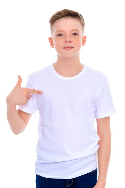 Ein Schuljunge zeigt auf sein weißes T-Shirt. — Stockfoto