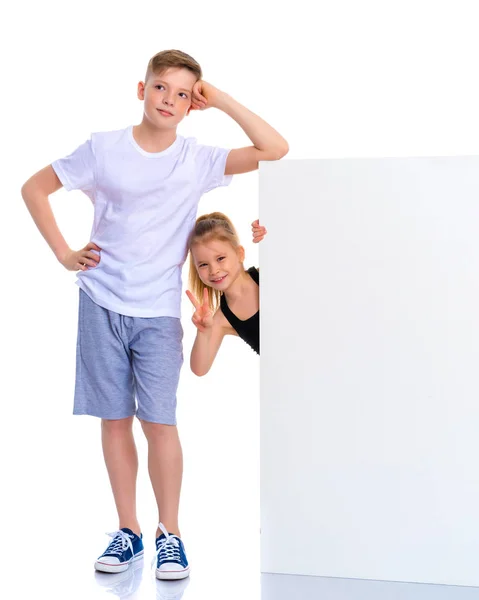 Un niño y una niña cerca de una pancarta blanca publicitaria . — Foto de Stock