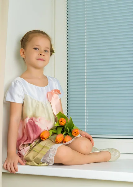 Een meisje zit op de vensterbank met een boeket van tul — Stockfoto