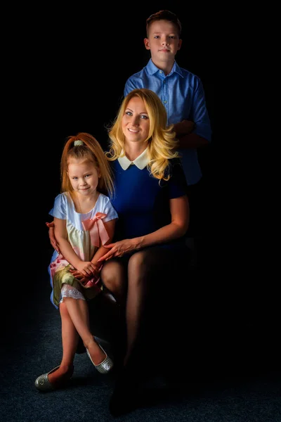 Glückliche junge Mutter mit ihrem Sohn und ihrer Tochter auf schwarzem Hintergrund — Stockfoto