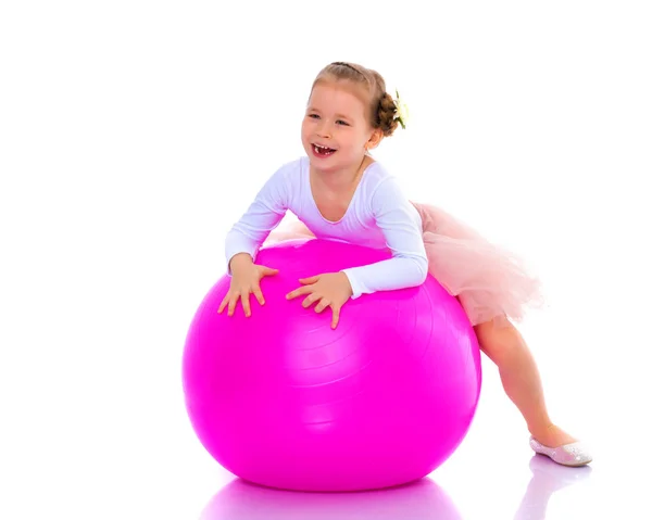 Kleines Mädchen macht Übungen auf einem großen Ball für Fitness. — Stockfoto