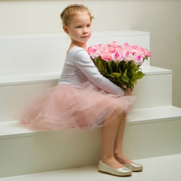 一束鲜花的小女孩坐在白色的楼梯上. — 图库照片