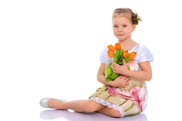 Bambina con mazzo di fiori si siede sul pavimento . — Foto Stock