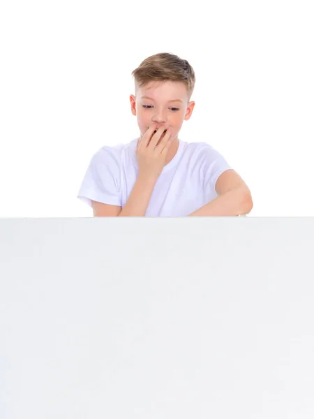 Un niño en edad escolar cerca de una pancarta publicitaria blanca . —  Fotos de Stock