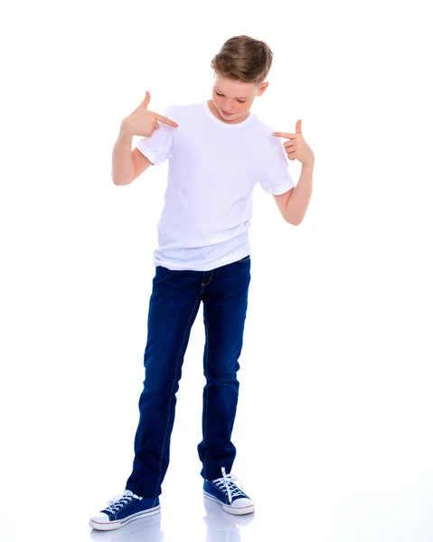 En skola pojke pekar på sin vita T-shirt. — Stockfoto