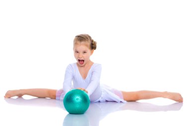 Küçük kız spor yapmak için büyük bir top üzerinde egzersiz yapıyor..