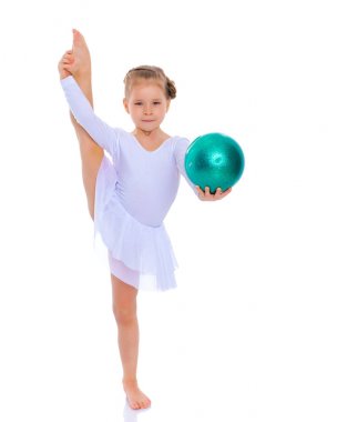 Küçük kız spor yapmak için büyük bir top üzerinde egzersiz yapıyor..