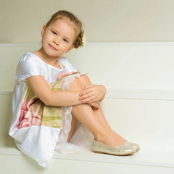 Красива маленька дівчинка сидить на білих сходах . — стокове фото