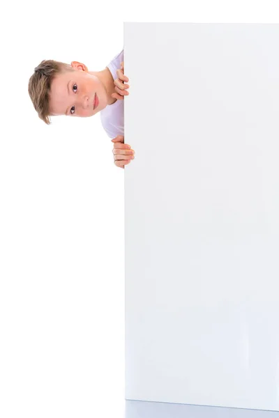 Um menino em idade escolar perto de um banner publicitário branco . — Fotografia de Stock
