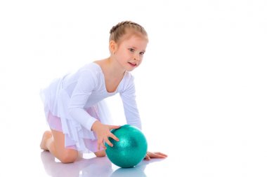 Küçük kız spor yapmak için büyük bir top üzerinde egzersiz yapıyor..